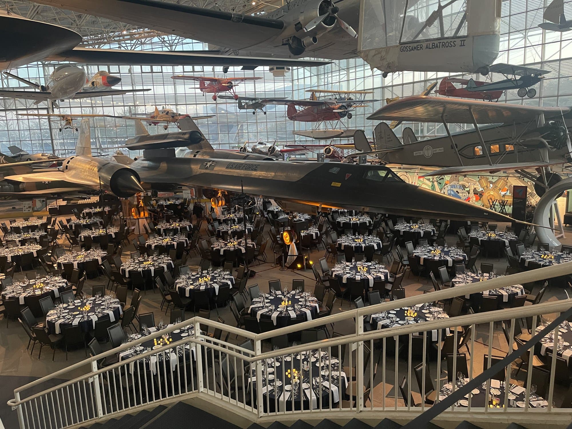 An Emily's Events reception in an aviation museum — vintage aircraft suspended above formally set banquet tables