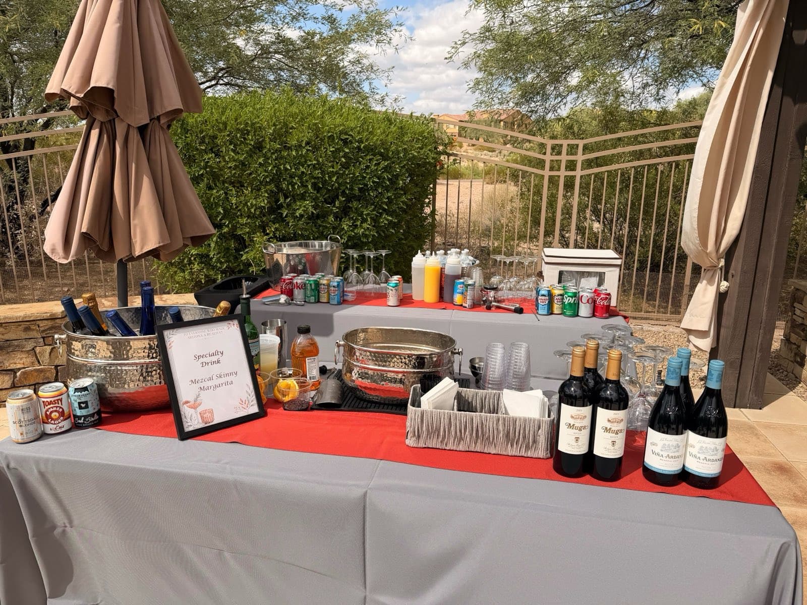 An outdoor bar set with wine, local Arizona beers and a specialty margarita sign, overlooking the desert