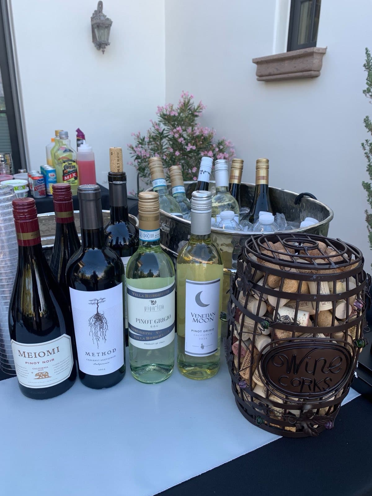 Red and white wine bottles beside a basket of wine corks on an Emily's Events bar