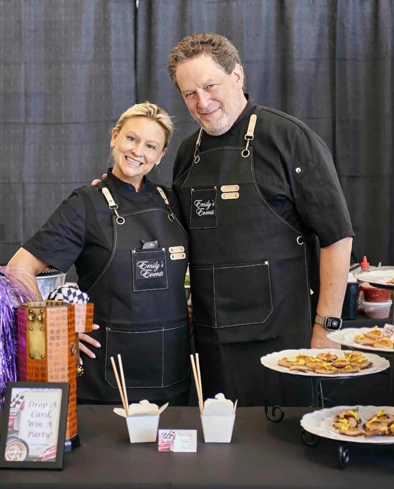 Emily and Rick in Emily's Events aprons at an event catering booth
