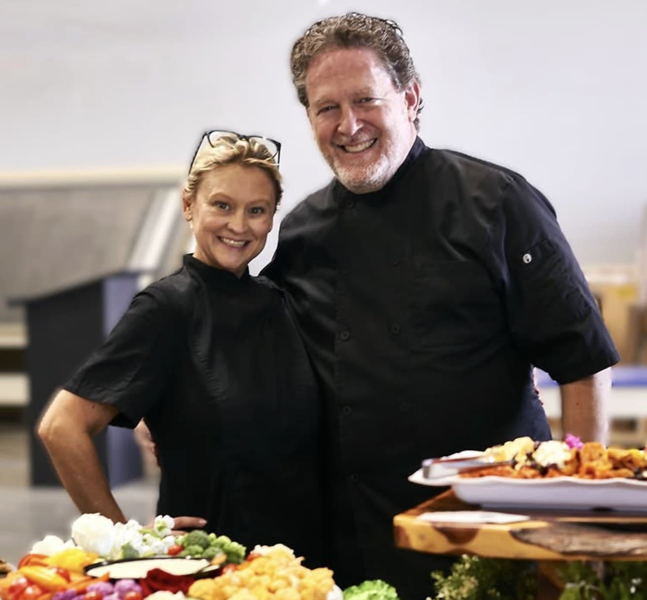 Emily Garner and Rick standing together in their kitchen, surrounded by charcuterie boards