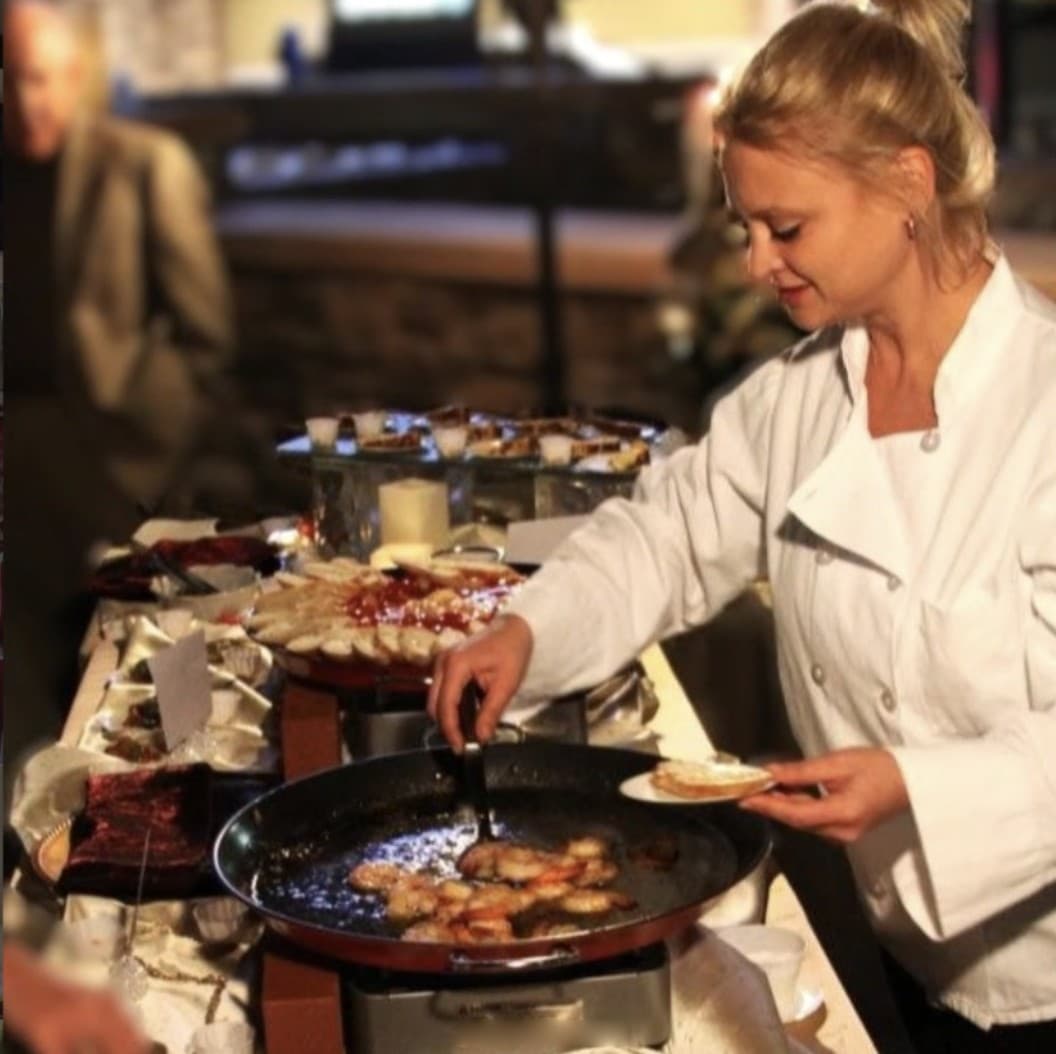 Emily Garner in chef whites, cooking shrimp at a live station during an event