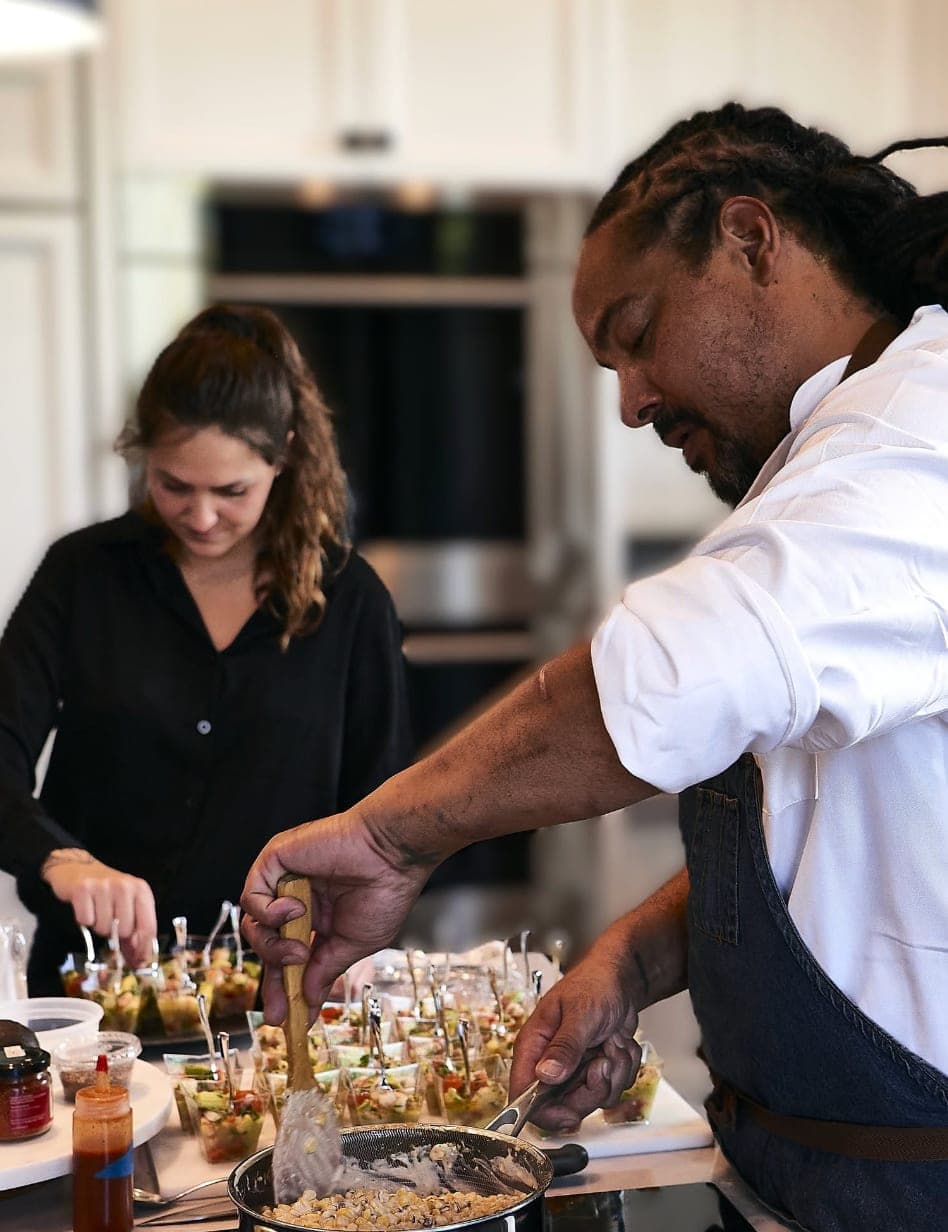 Two staff members assembling appetizer cups in a kitchen during service