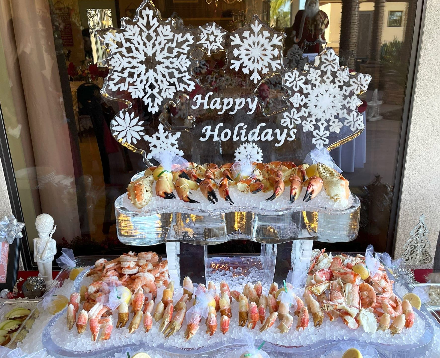 A 'Happy Holidays' ice sculpture above a chilled seafood and shrimp display