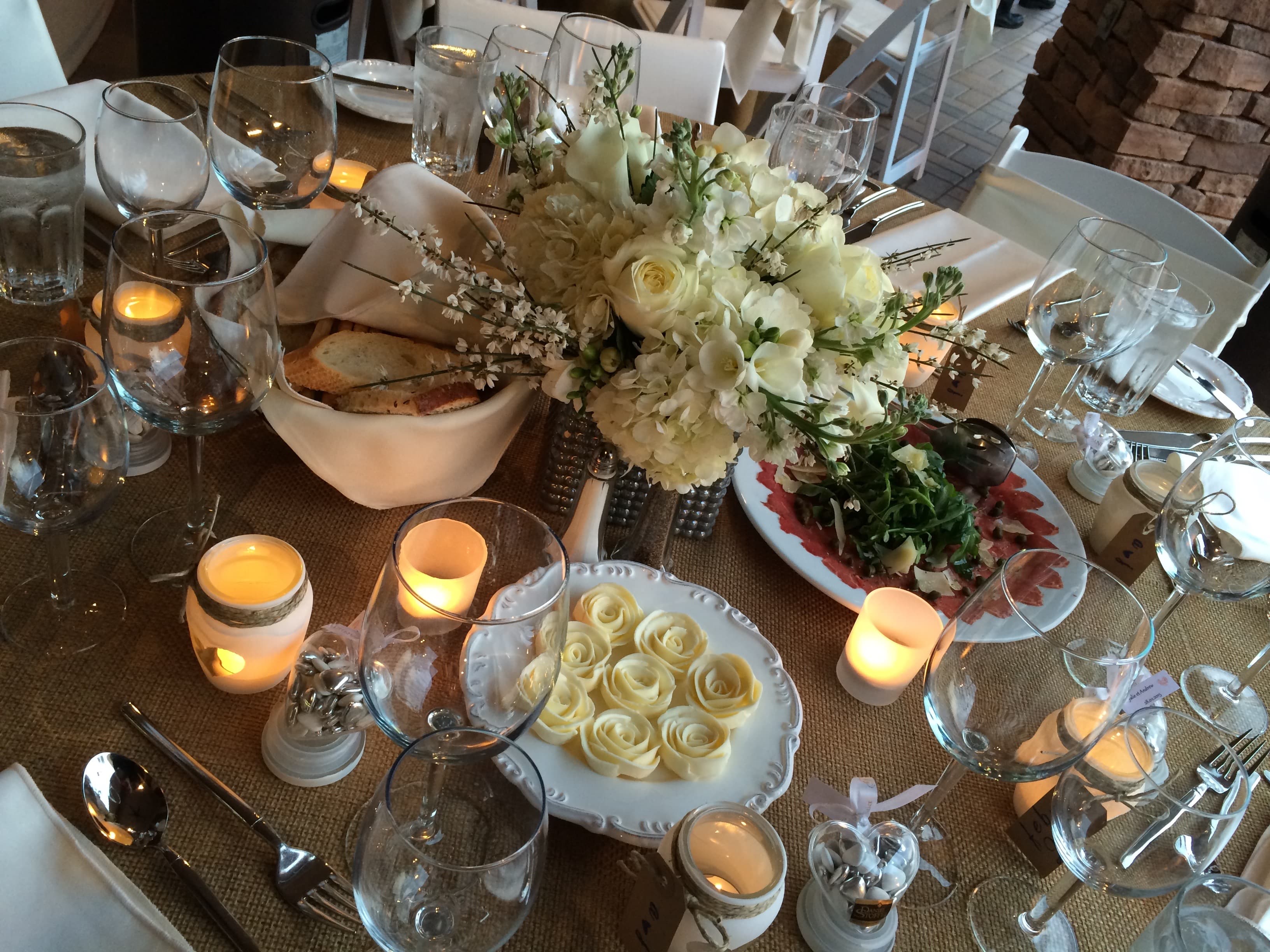 Candlelit dinner table with white roses and elegantly set place settings