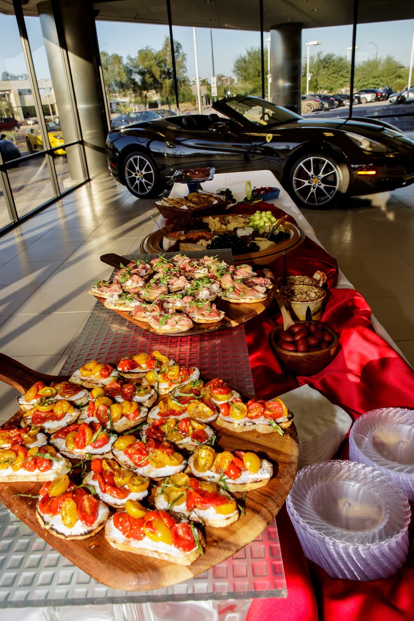 A catering spread of crostini in a luxury car showroom, a sports car behind
