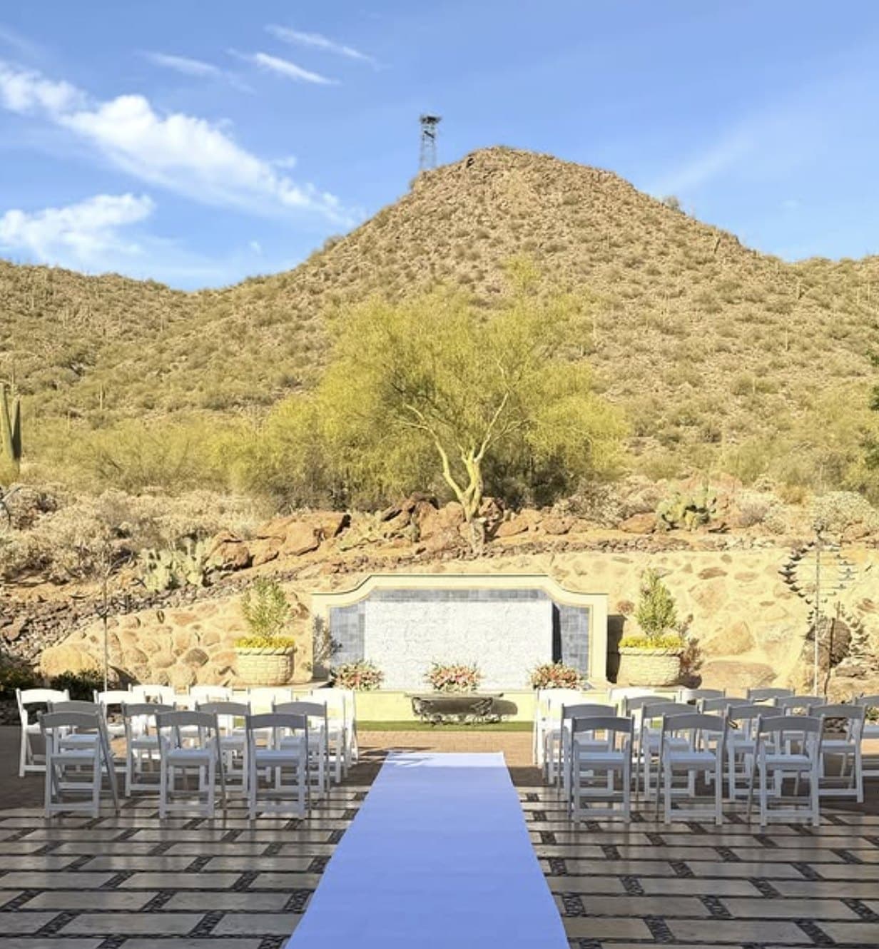 A desert wedding ceremony set for guests in the Sonoran foothills, with white chairs squared off either side of the aisle